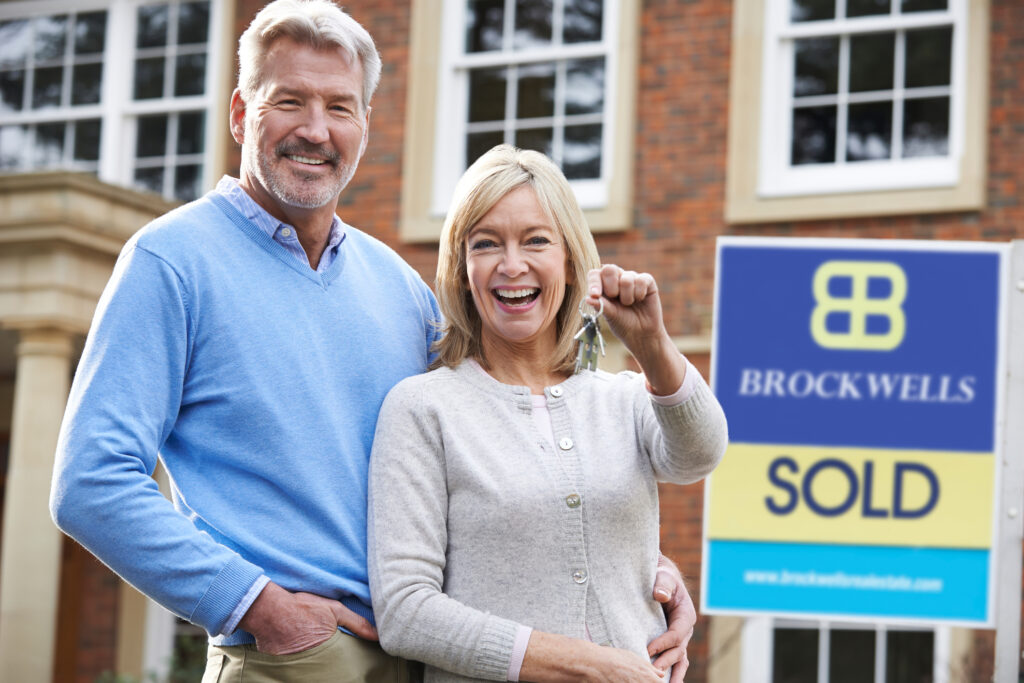 Home sellers in Naples, FL holding keys in front of house